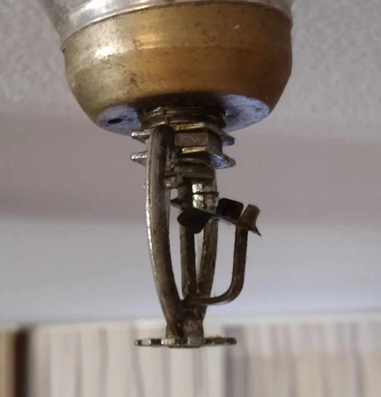 A fusible-link fire sprinkler head mounted in a ceiling