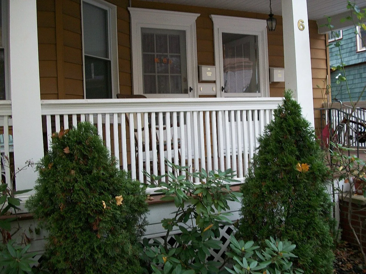 White porch railing and columns on a house (Photo: Tomwsulcer / Wikimedia Commons, public domain)