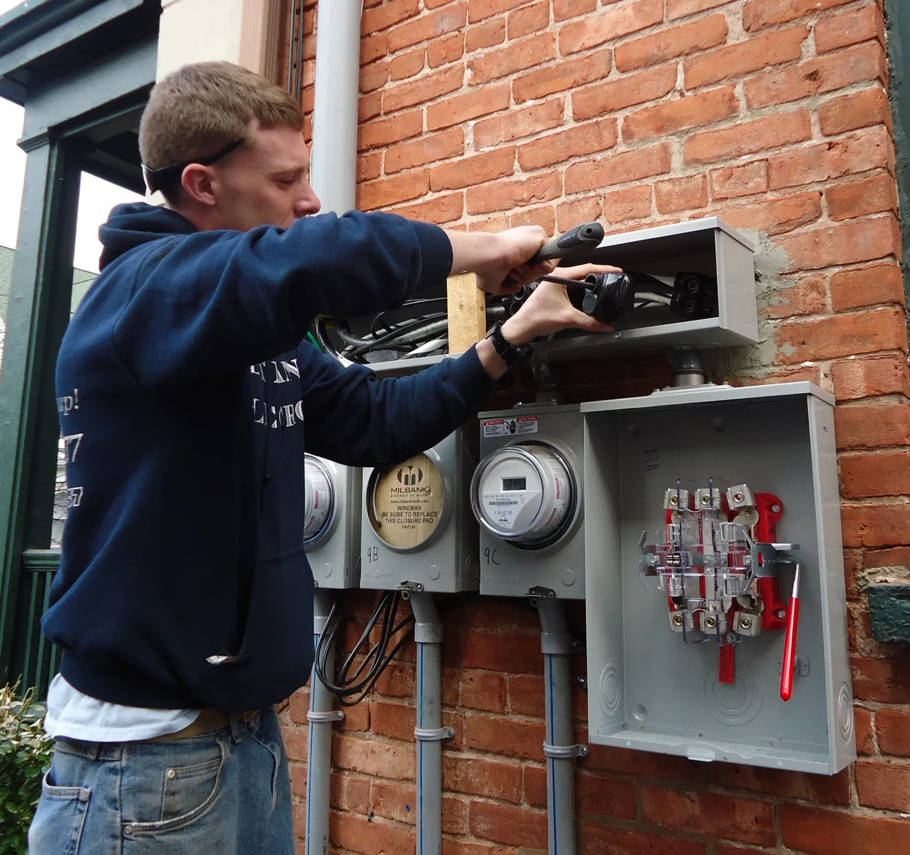 An electrician upgrading exterior service panels on a multifamily house